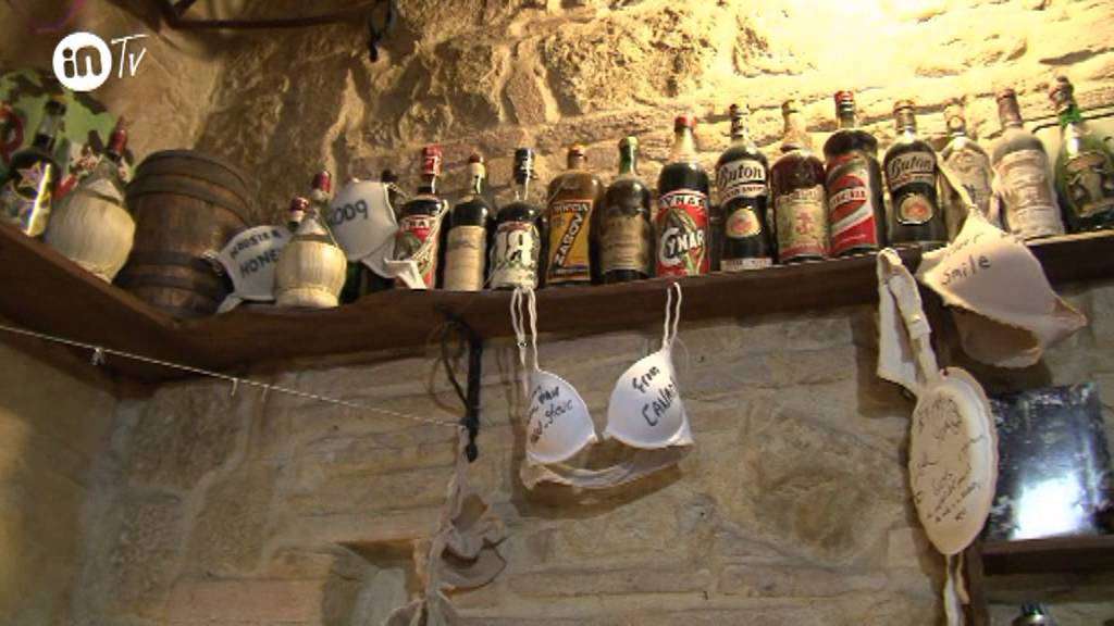 Interno della Vena di Vino a Volterra con mensola di bottiglie vintage e pareti in pietra (dicembre 2013)